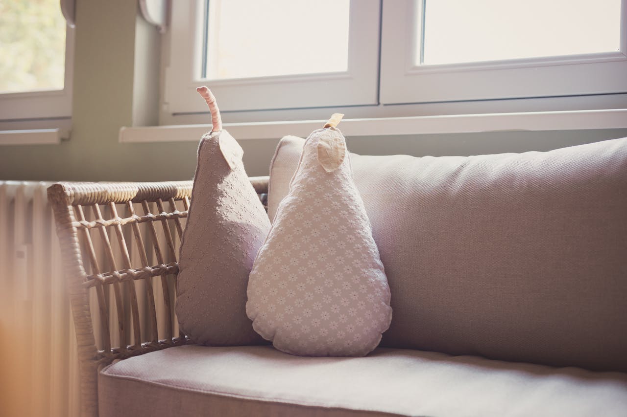 Comfortable indoor seating with pear shaped cushions on a wicker chair by a sunlit window.